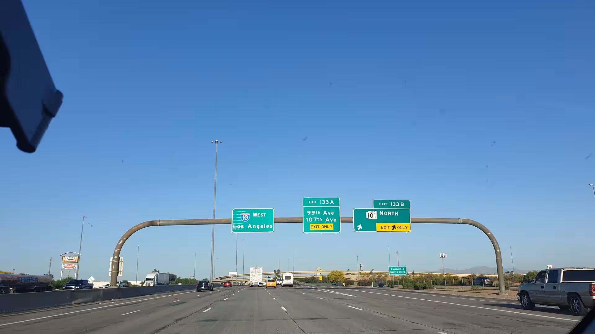 Green gantry signs direct traffic along an Arizona interstate toward Los Angeles.