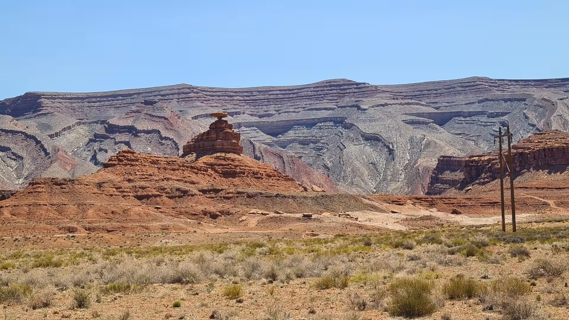A flat-topped rock balances like a capstone on a red butte before layered grey and red canyon walls.