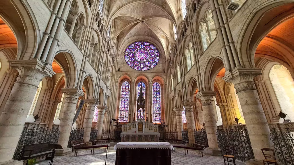 Tall stone columns and pointed arches frame a glowing rose window.