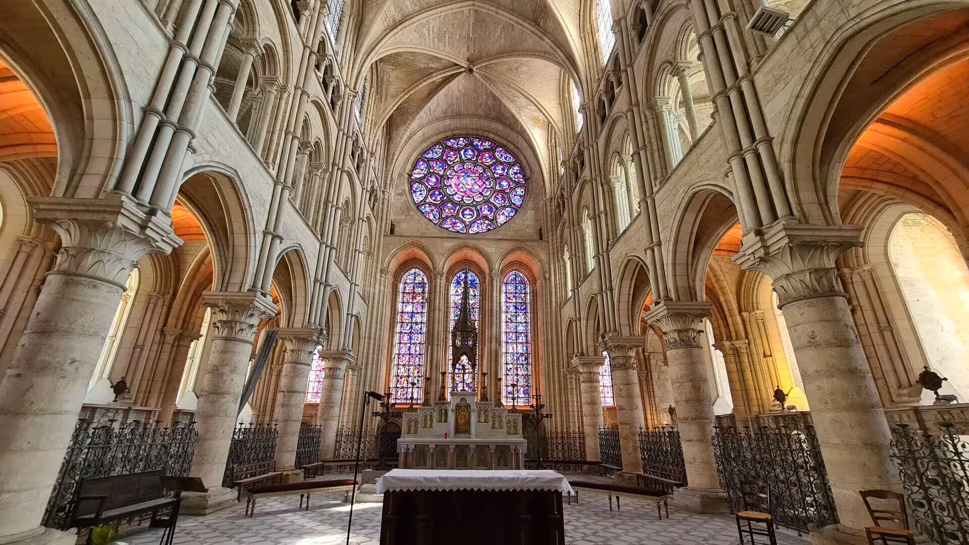 Tall stone columns and pointed arches frame a glowing rose window.