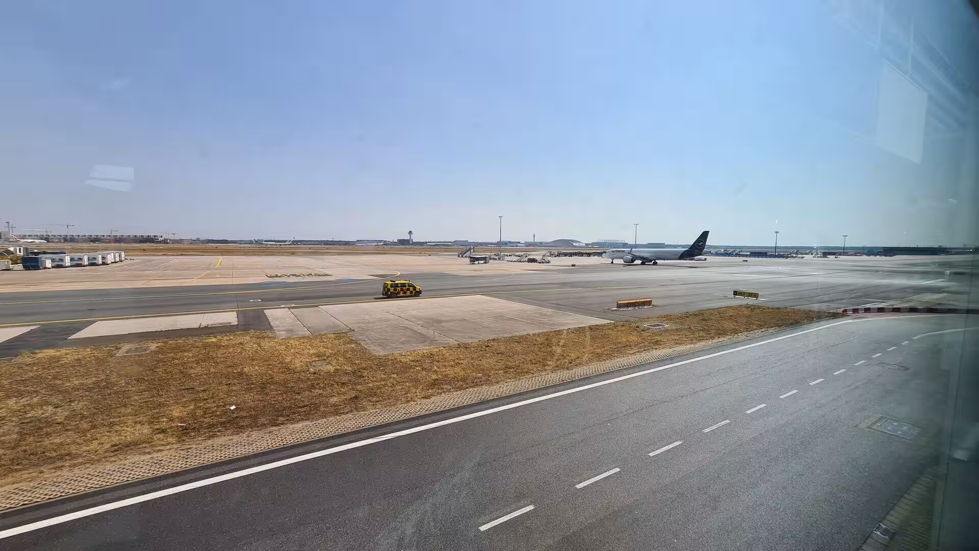 An open expanse of concrete taxiways and dry grass lies beneath a cloudless sky