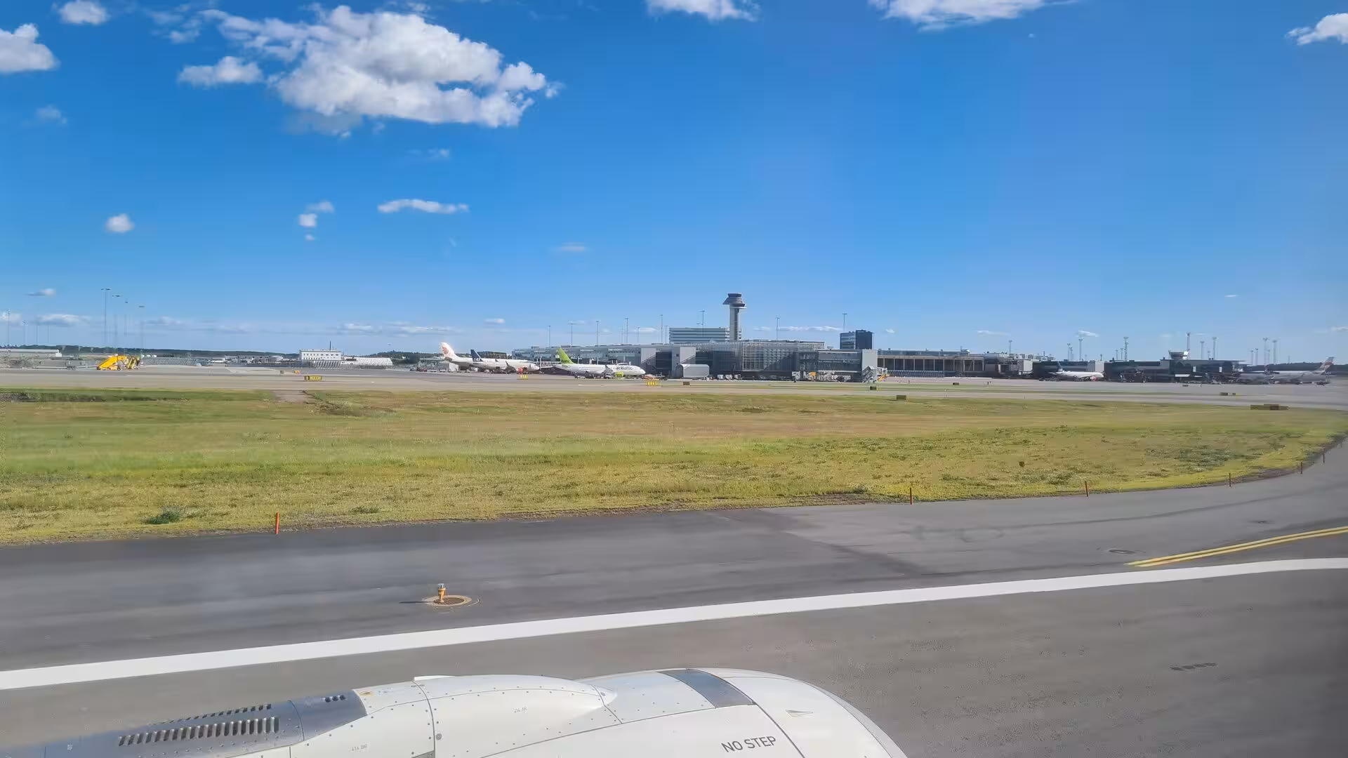 Grassy airfield and an airport control tower spread out beyond the aircraft engine