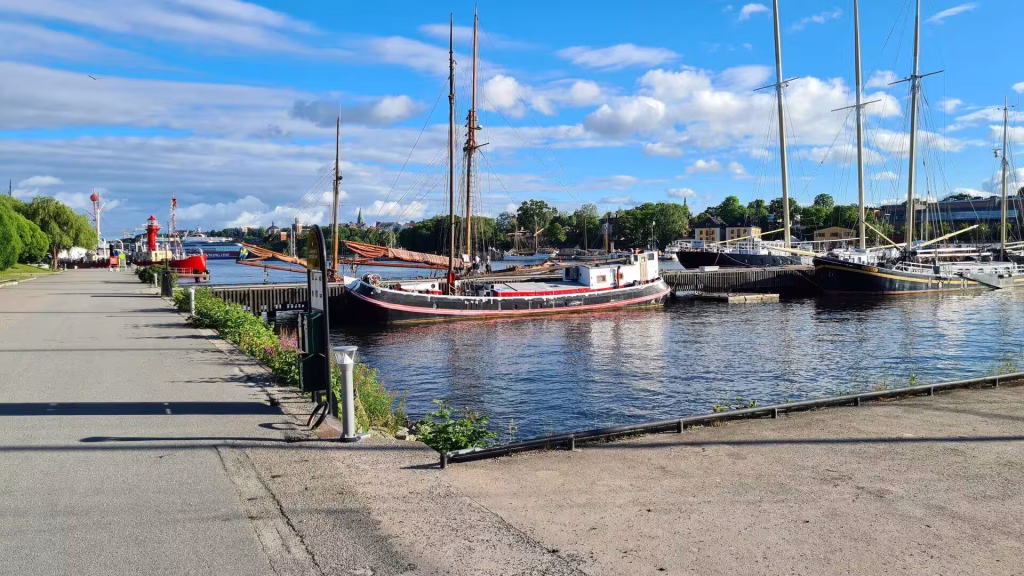 Tall sailing ships rest at quiet wooden piers along the waterfront.