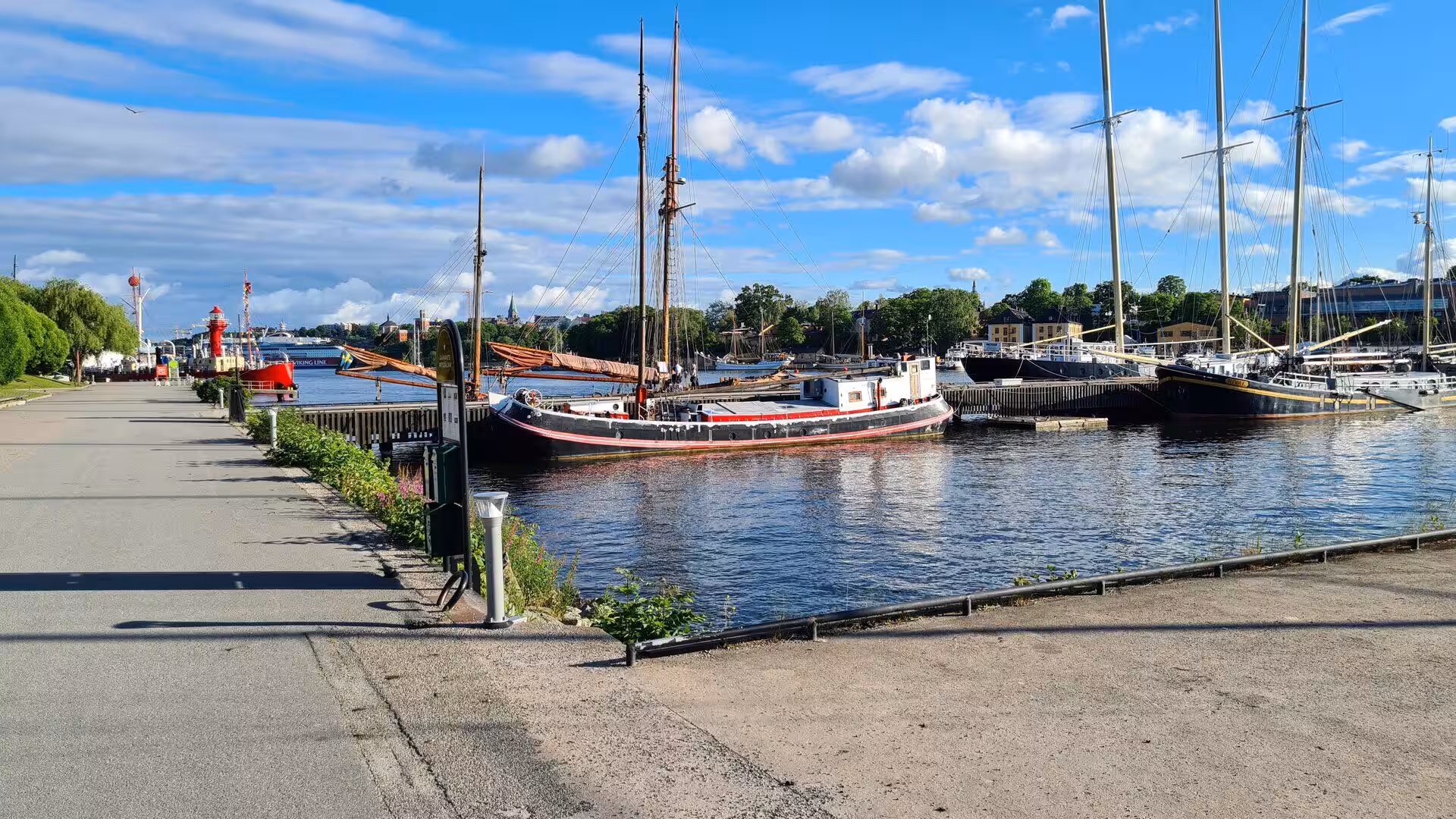 Tall sailing ships rest at quiet wooden piers along the waterfront.