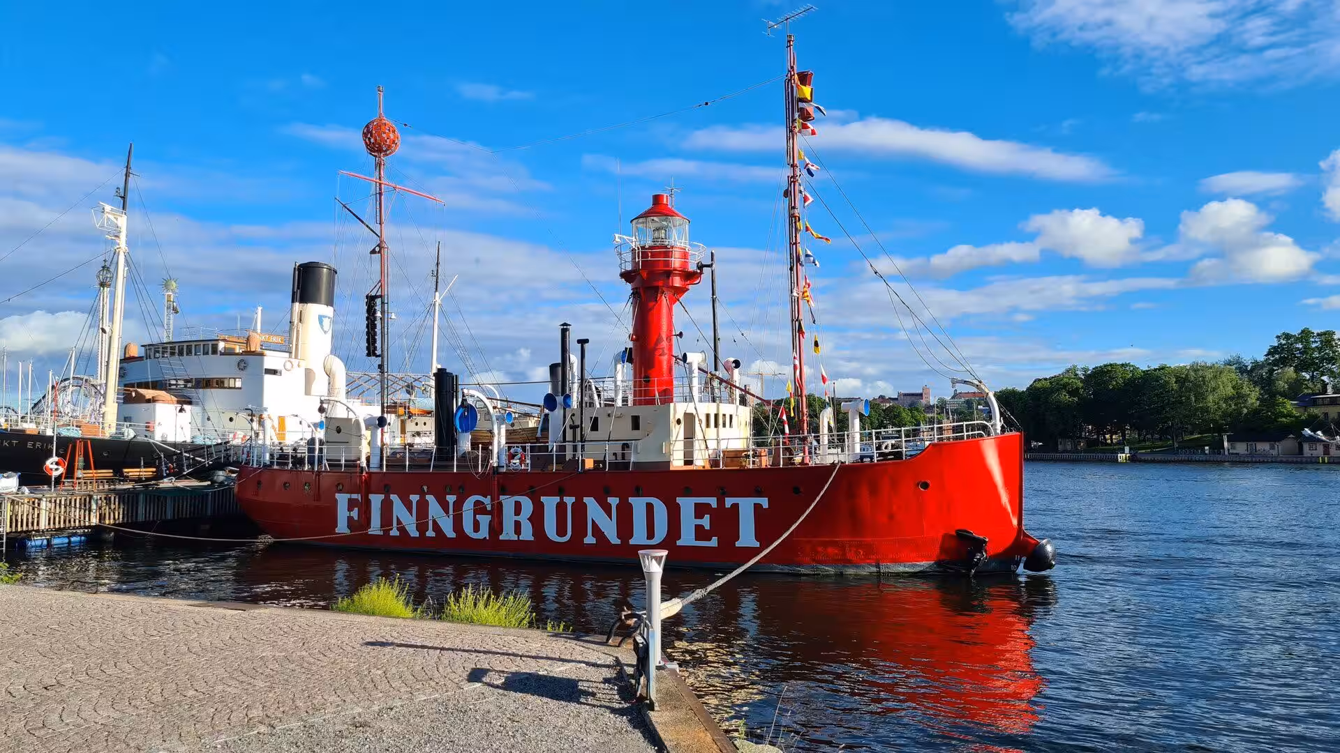 The bright red lightship Finngrundet glows in the harbor sunshine.