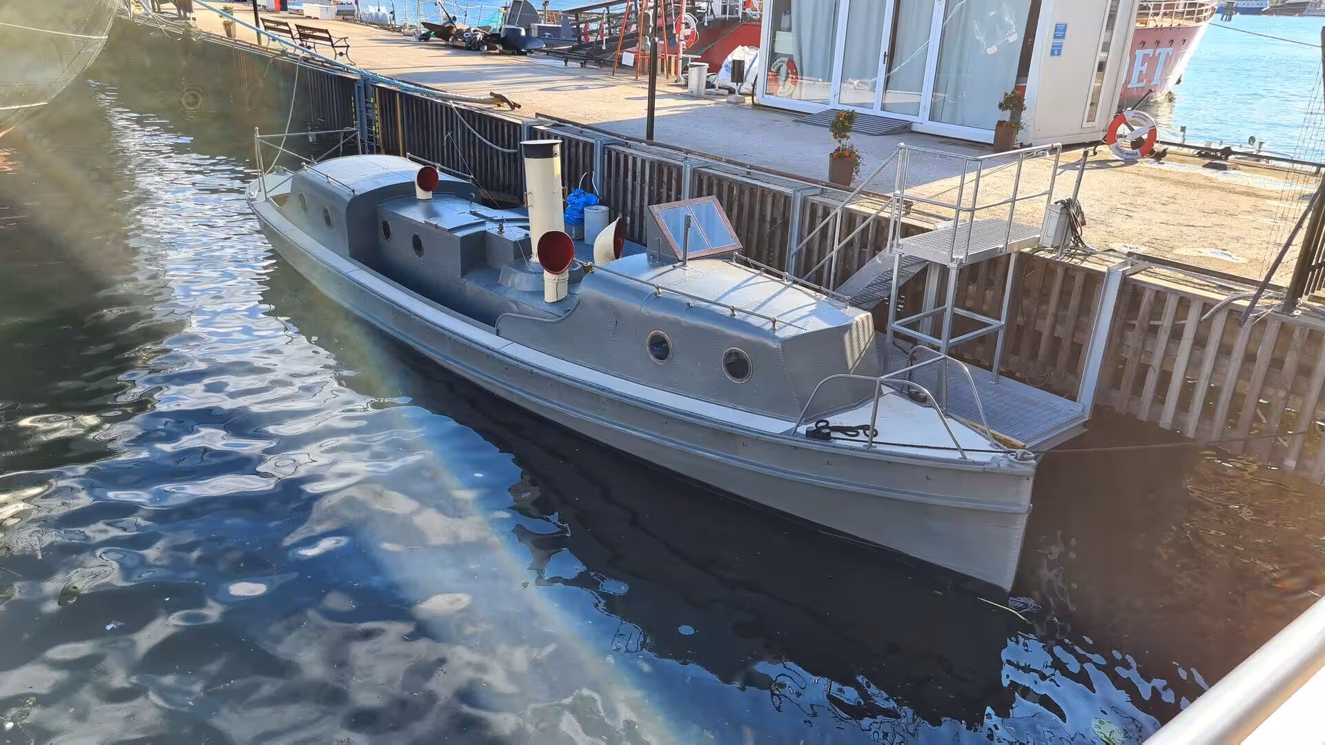 A small grey wooden launch floats quietly beside the boarding ramp.