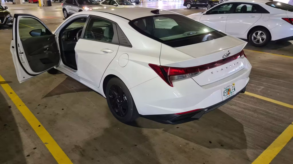 A white sedan with both doors open in a parking structure.