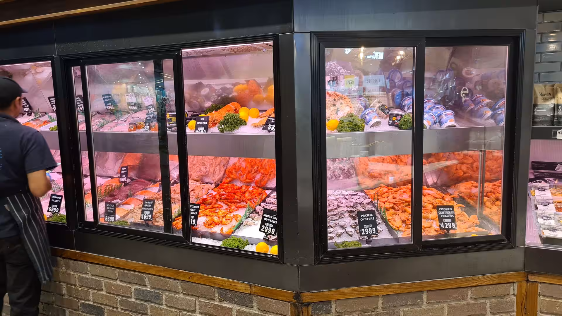 Glass display cases are piled with prawns, oysters and salmon at a fish market counter