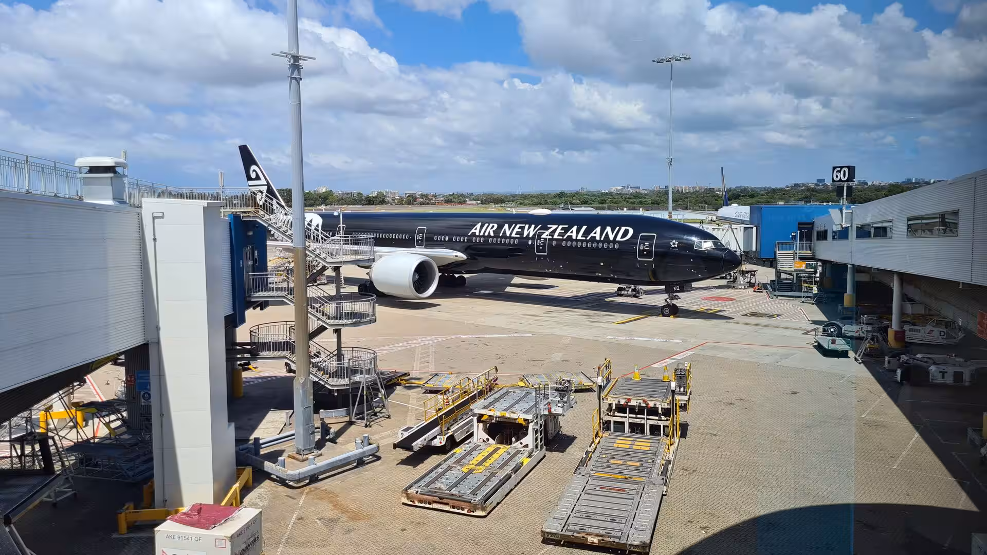 A sleek black Air New Zealand airliner parked at the boarding gate.