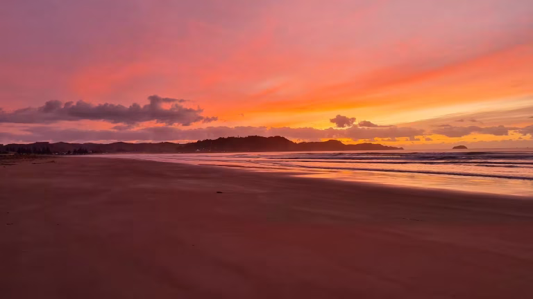 Vivid sunset glow over a wide ocean beach.