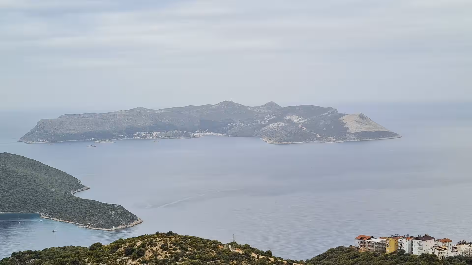 A calm bay spreads toward a hazy headland.