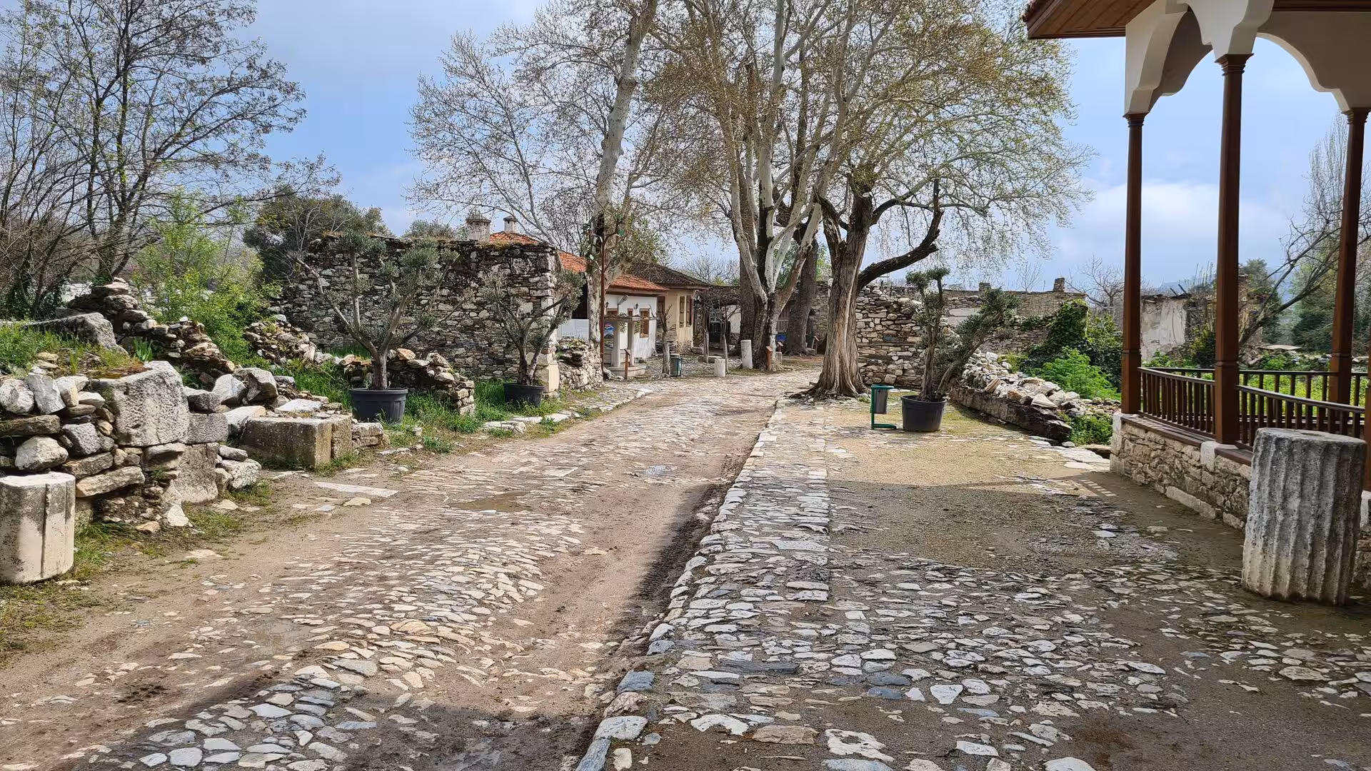 A cobbled path winds past old stone houses and ruins.