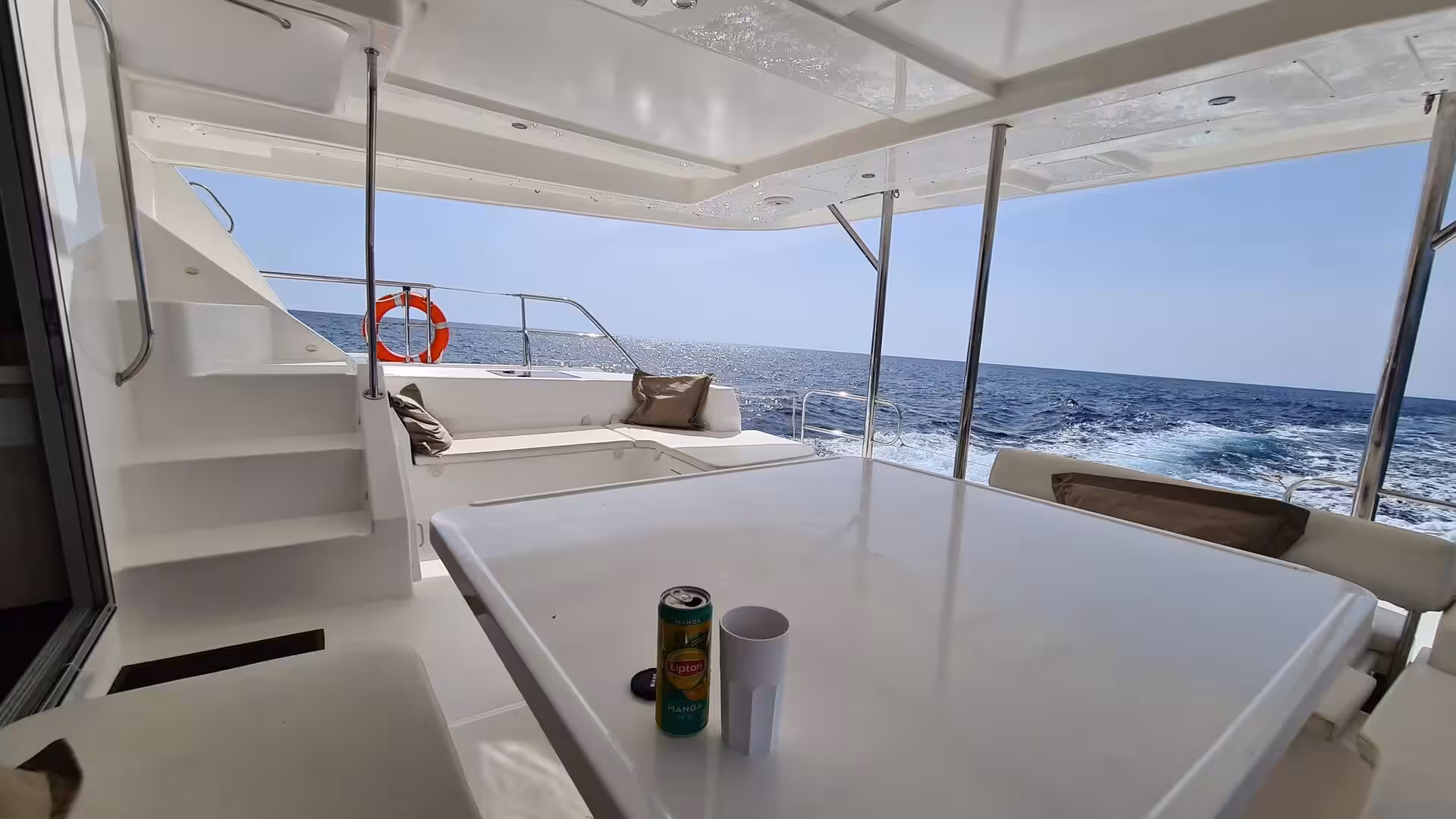A white boat deck holds a table with a drink can and cup.