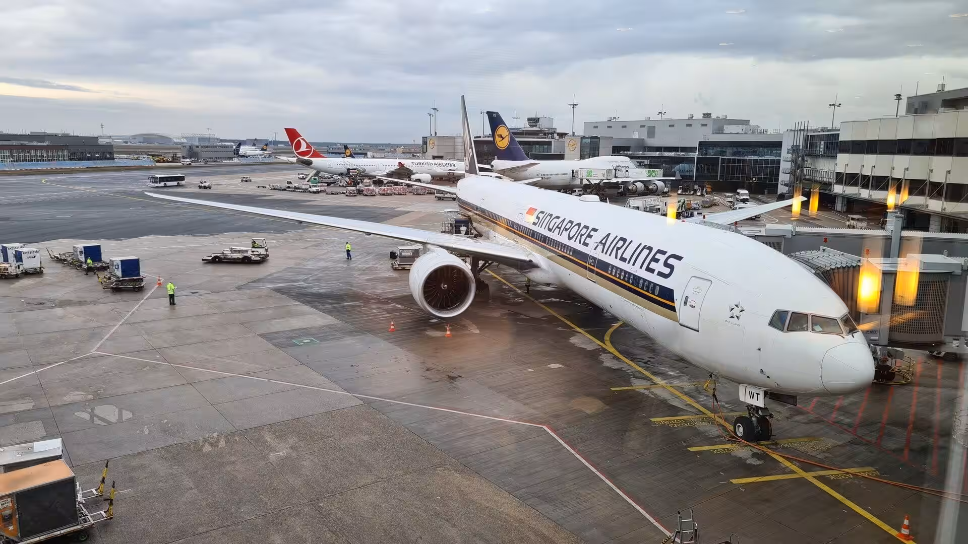 A Singapore Airlines aircraft waits at the gate while other planes line the tarmac.