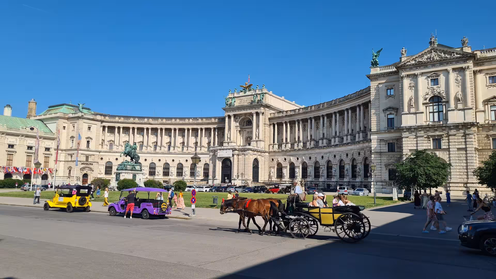 A horse-drawn fiaker carriage passes Vienna's grand neoclassical palace facade on a sunny day.