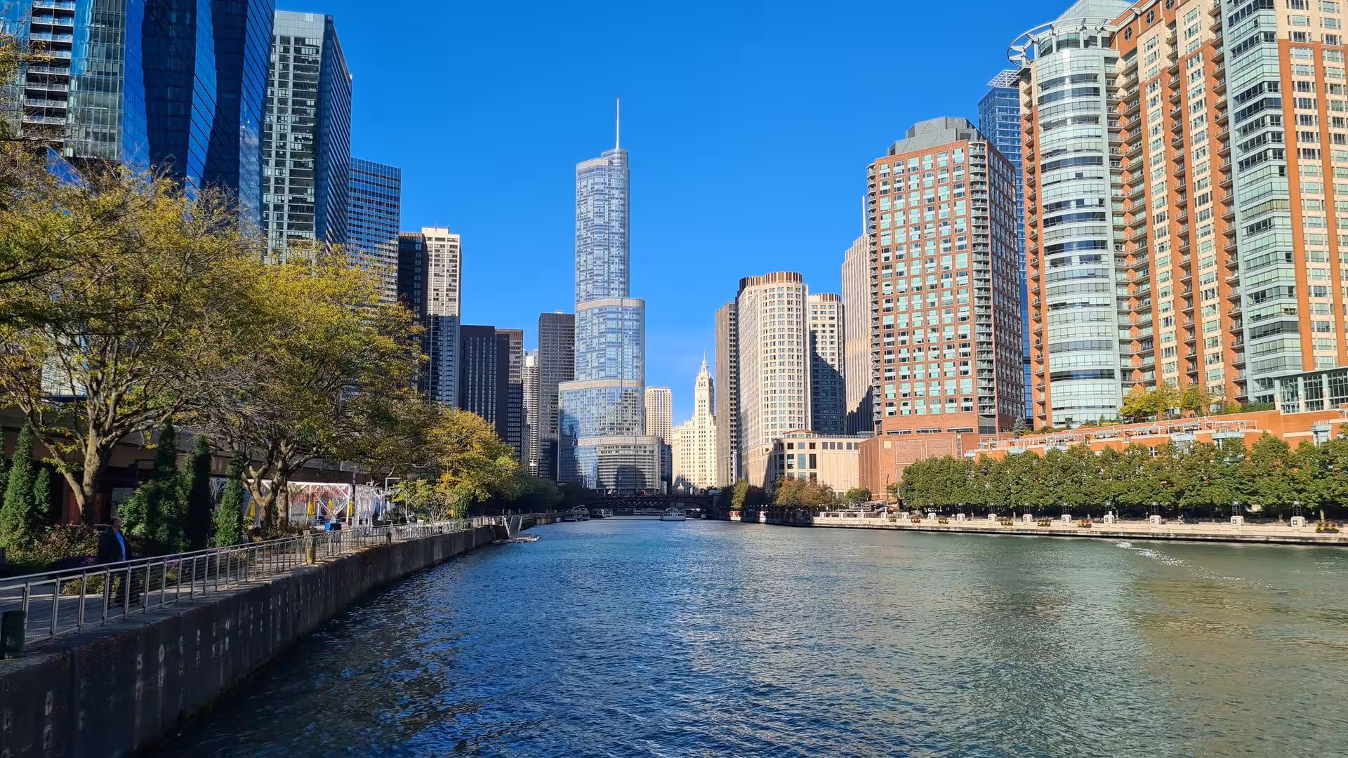 View along the Chicago River with modern skyscrapers, waterfront promenades, and the Trump International Hotel & Tower rising above downtown Chicago.