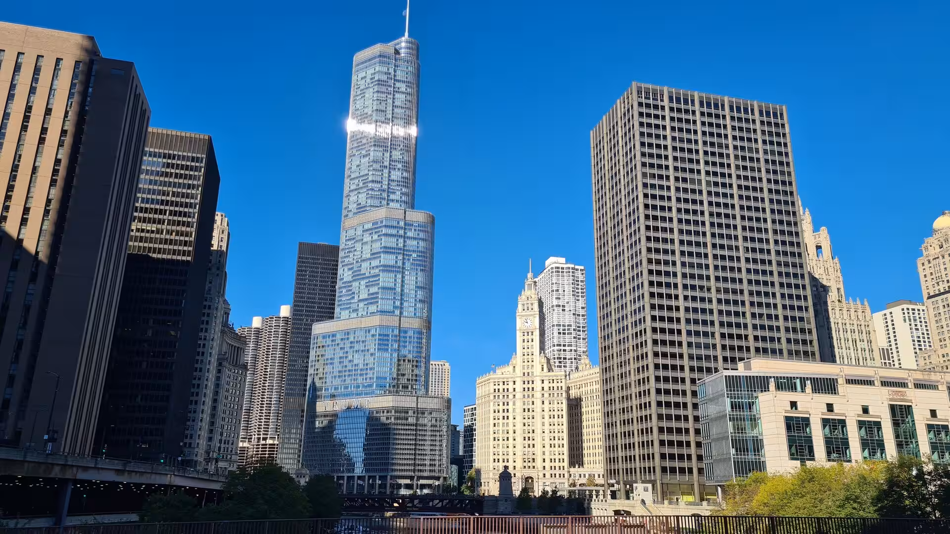 Downtown Chicago skyline featuring Trump International Hotel & Tower, the Wrigley Building clock tower, and surrounding skyscrapers along the Chicago River.