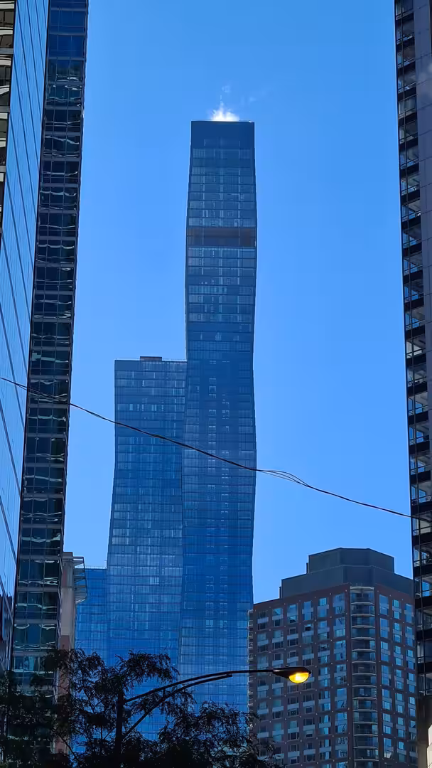 View of the St. Regis Chicago skyscraper rising above surrounding downtown buildings beneath a clear blue sky.