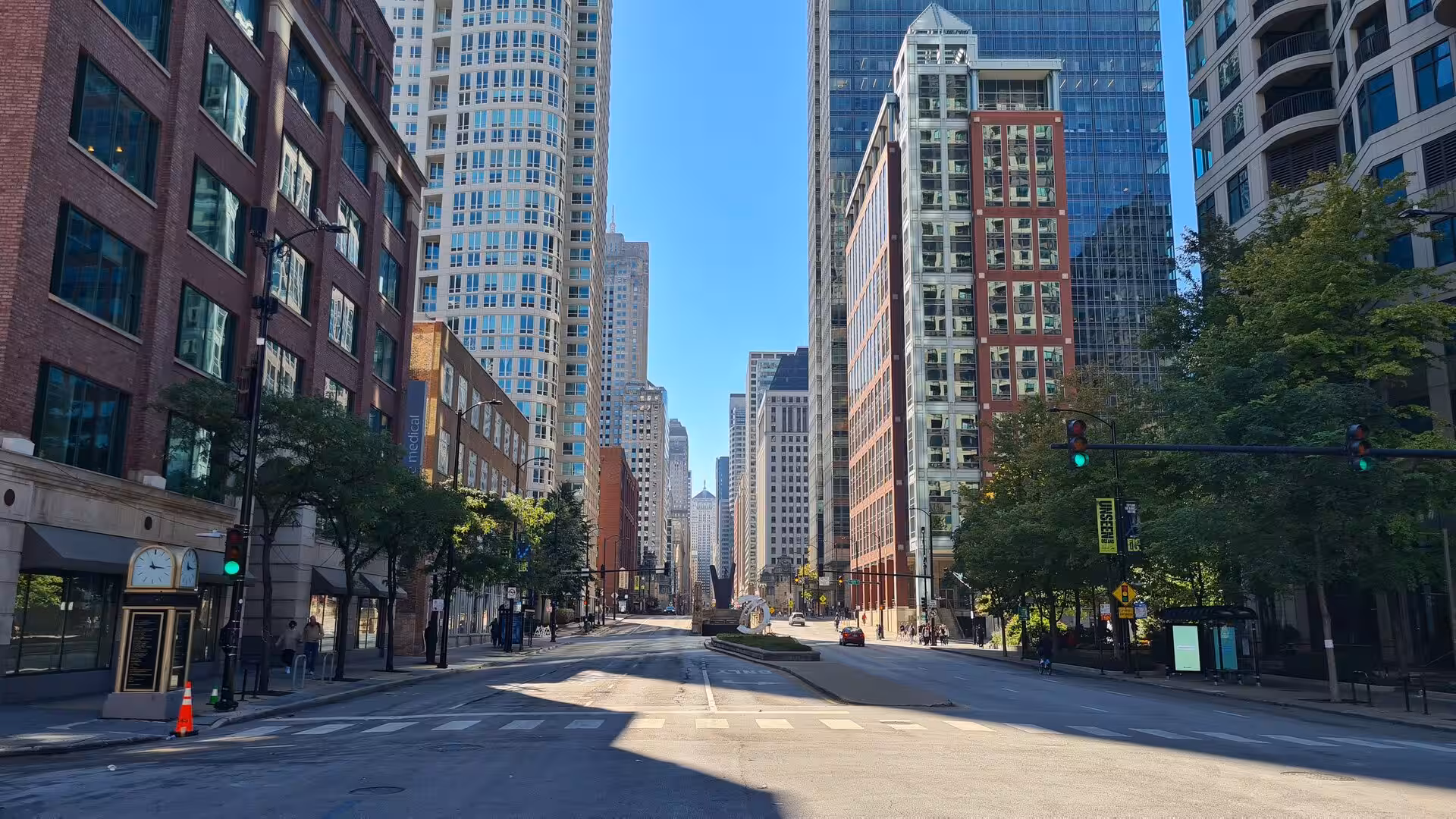 Downtown Chicago avenue lined with skyscrapers, modern office buildings, and historic architecture under a clear blue sky.