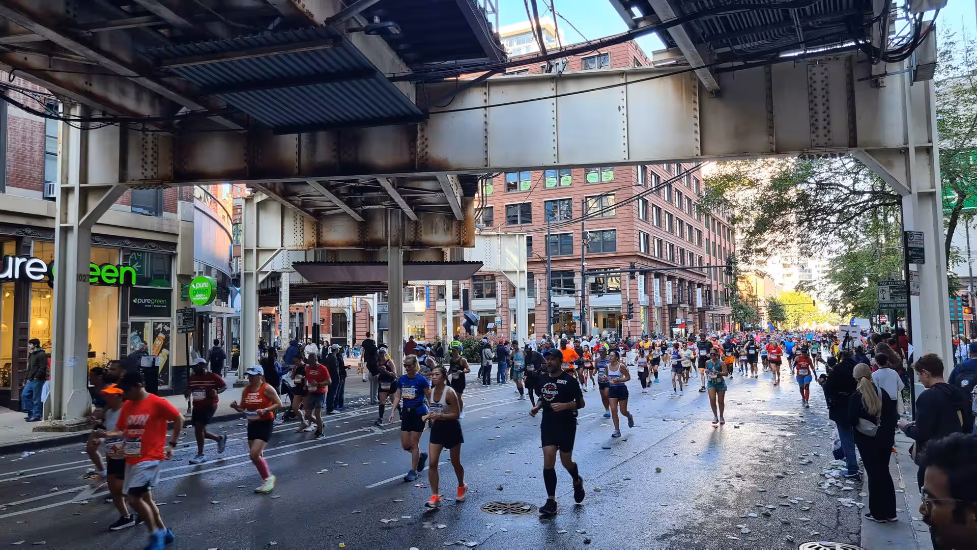 Thousands of runners participating in a marathon through downtown Chicago beneath the city’s iconic elevated railway tracks.