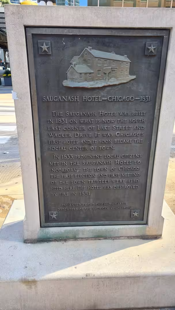 Historic bronze plaque marking the location of the Sauganash Hotel in downtown Chicago, describing its role as Chicago’s first hotel and an early meeting place in the city’s history.