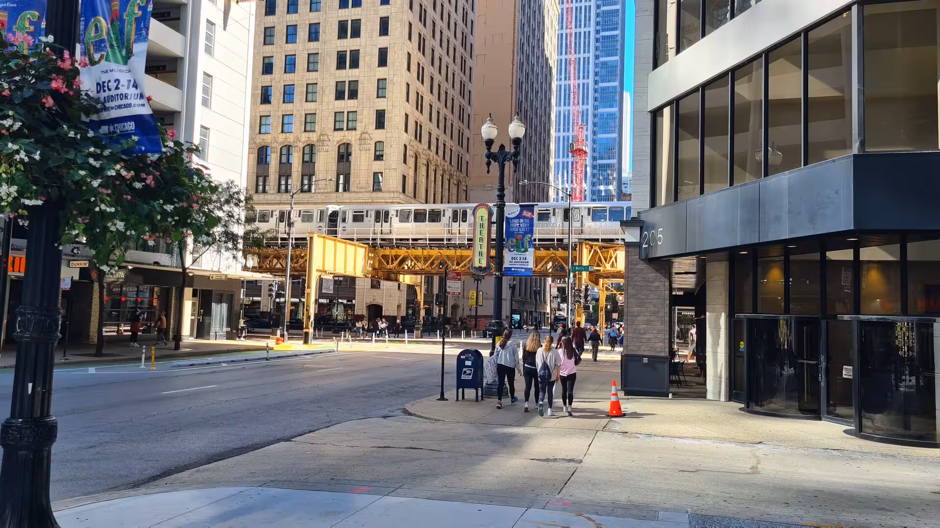 Street scene in downtown Chicago with an elevated CTA train crossing above the road between high-rise buildings in the Loop district.