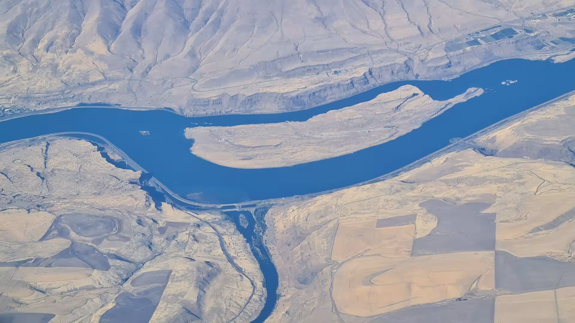 Aerial landscape of the Columbia River winding through dry canyon terrain and farmland