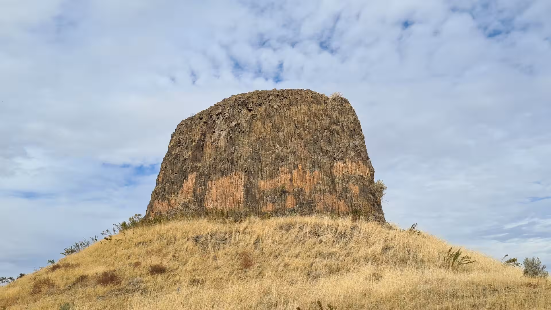 Volcanic basalt monolith rising above dry grassland at Hat Rock State Park in Oregon