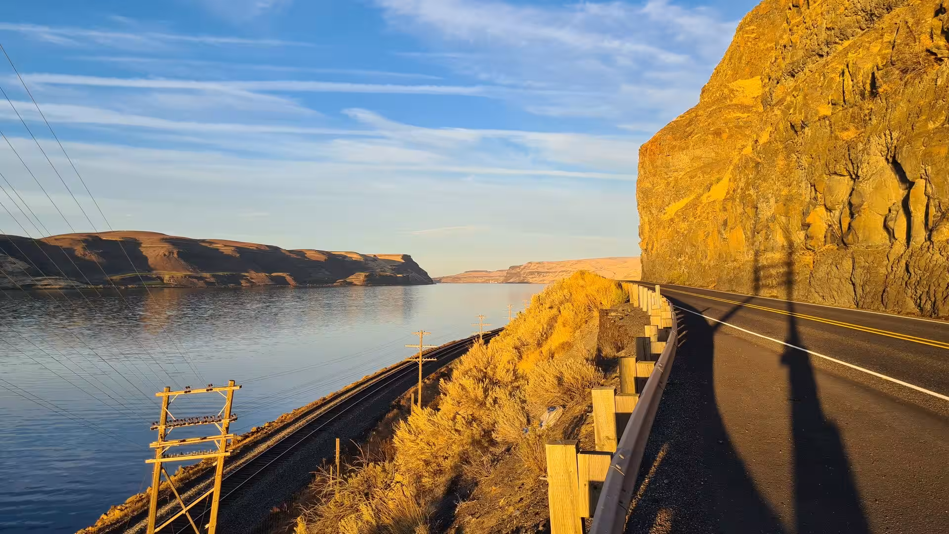 Road carved into towering basalt cliffs beside the Columbia River during warm evening light in eastern Washington