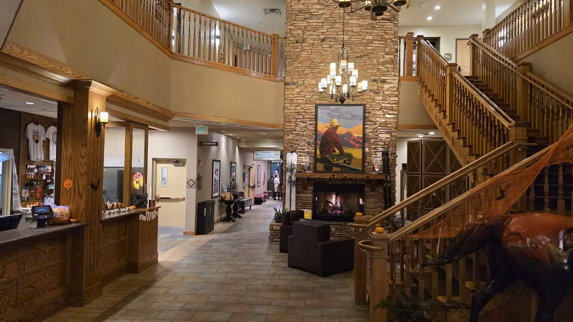 Mountain resort hotel lobby with stone fireplace and wooden staircase