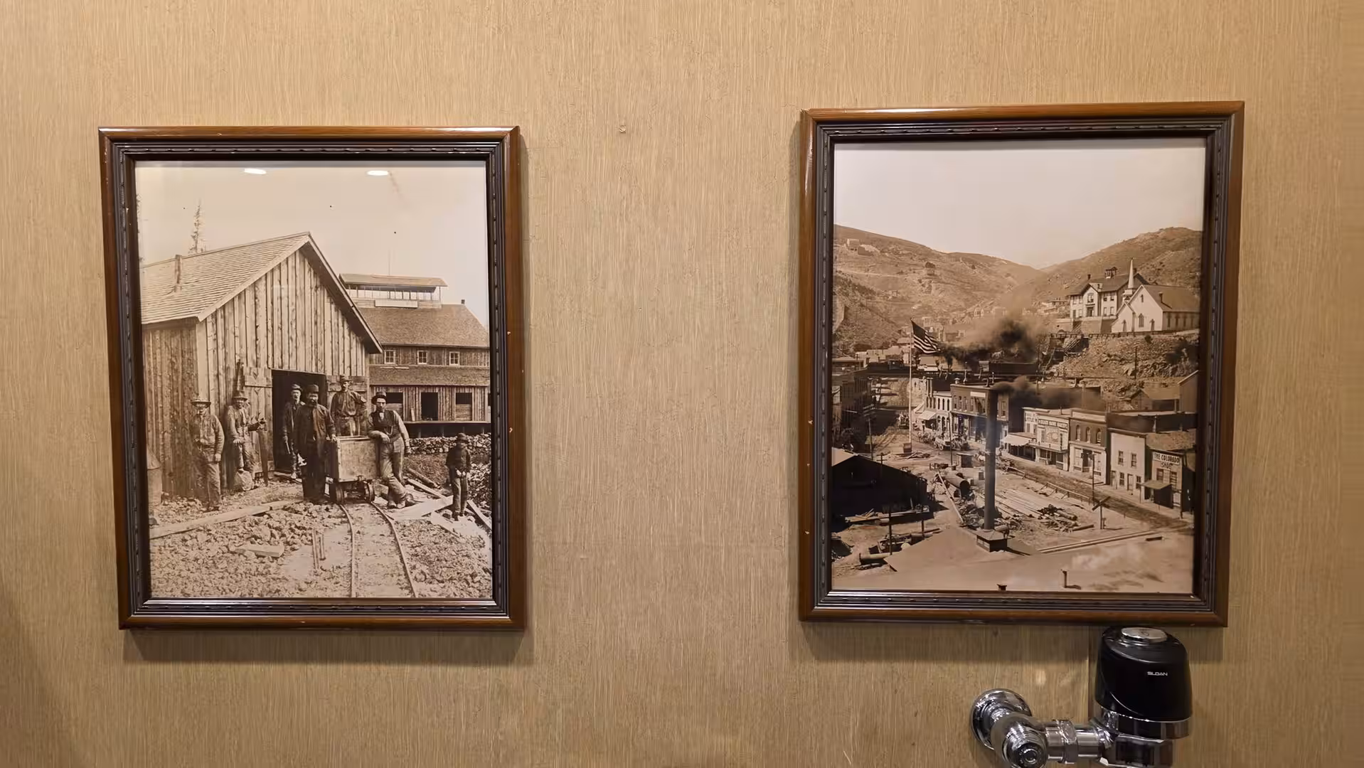 Framed historic mining town photographs displayed on a wall