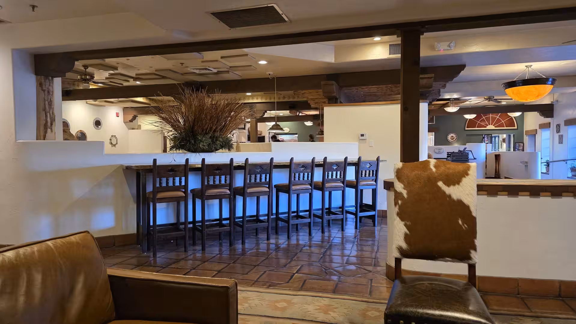 Southwestern hotel lounge with tiled floor, wooden beams and rustic bar seating