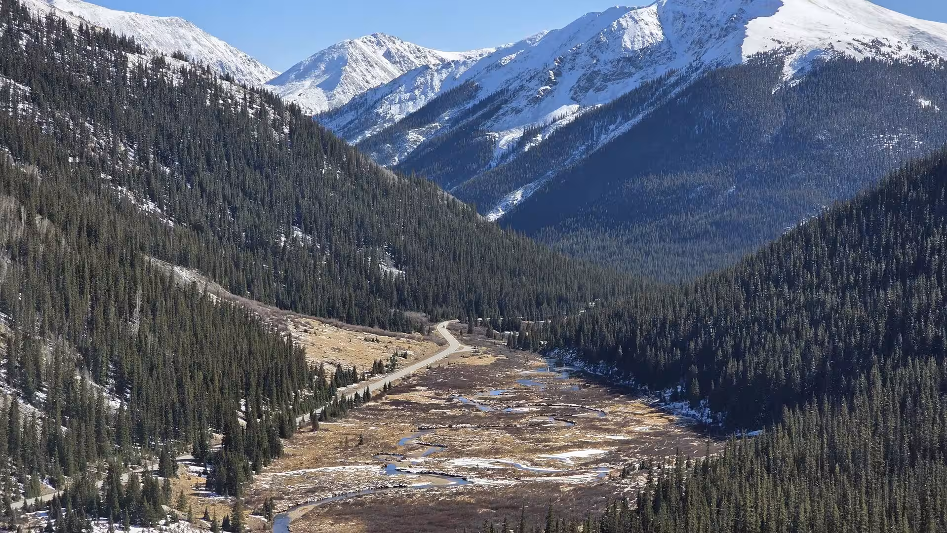 Snow-covered Rocky Mountain valley with winding road and evergreen forest near Independence Pass in Colorado