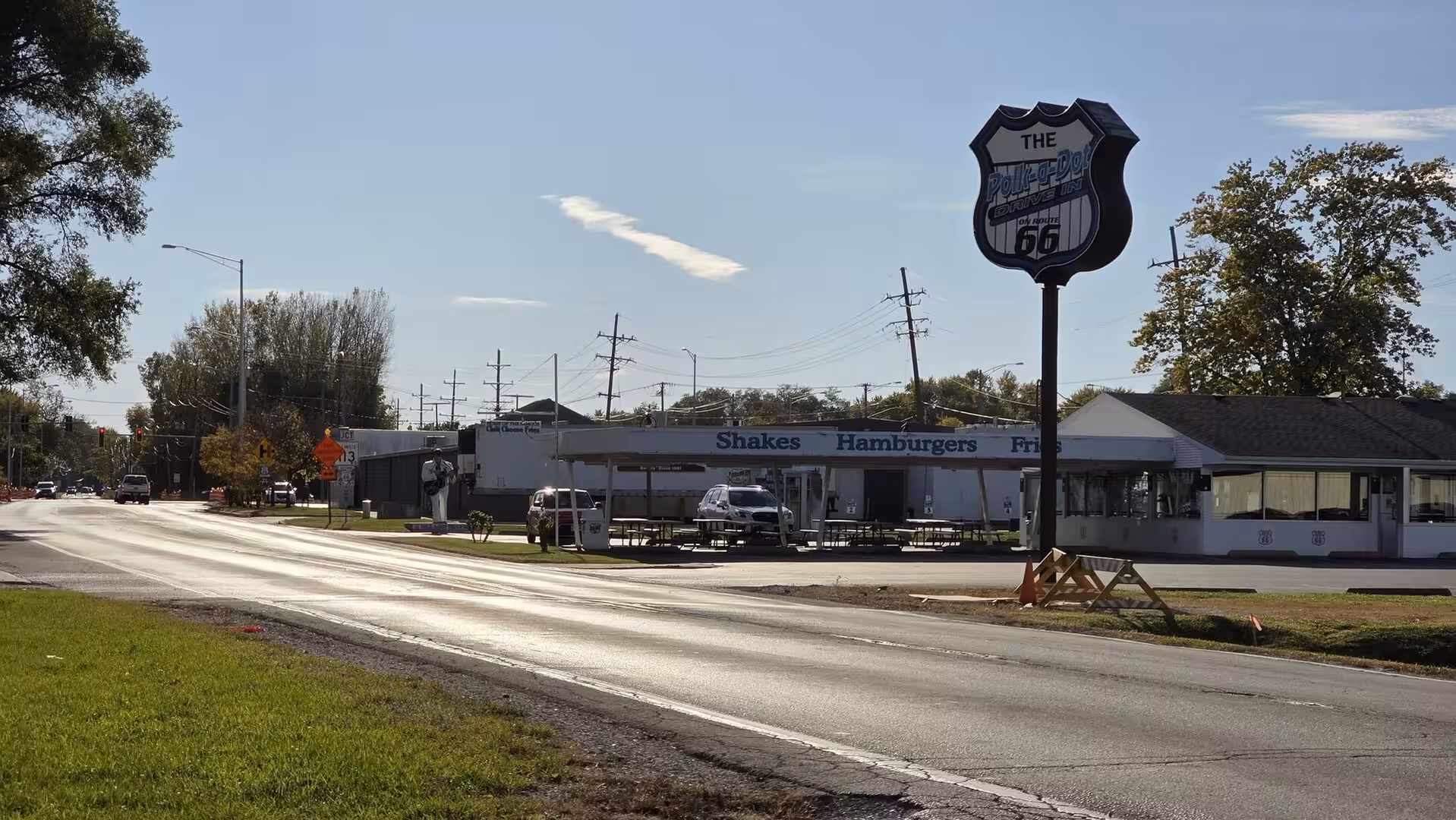 Historic Route 66-style roadside diner beside a sunlit American highway.