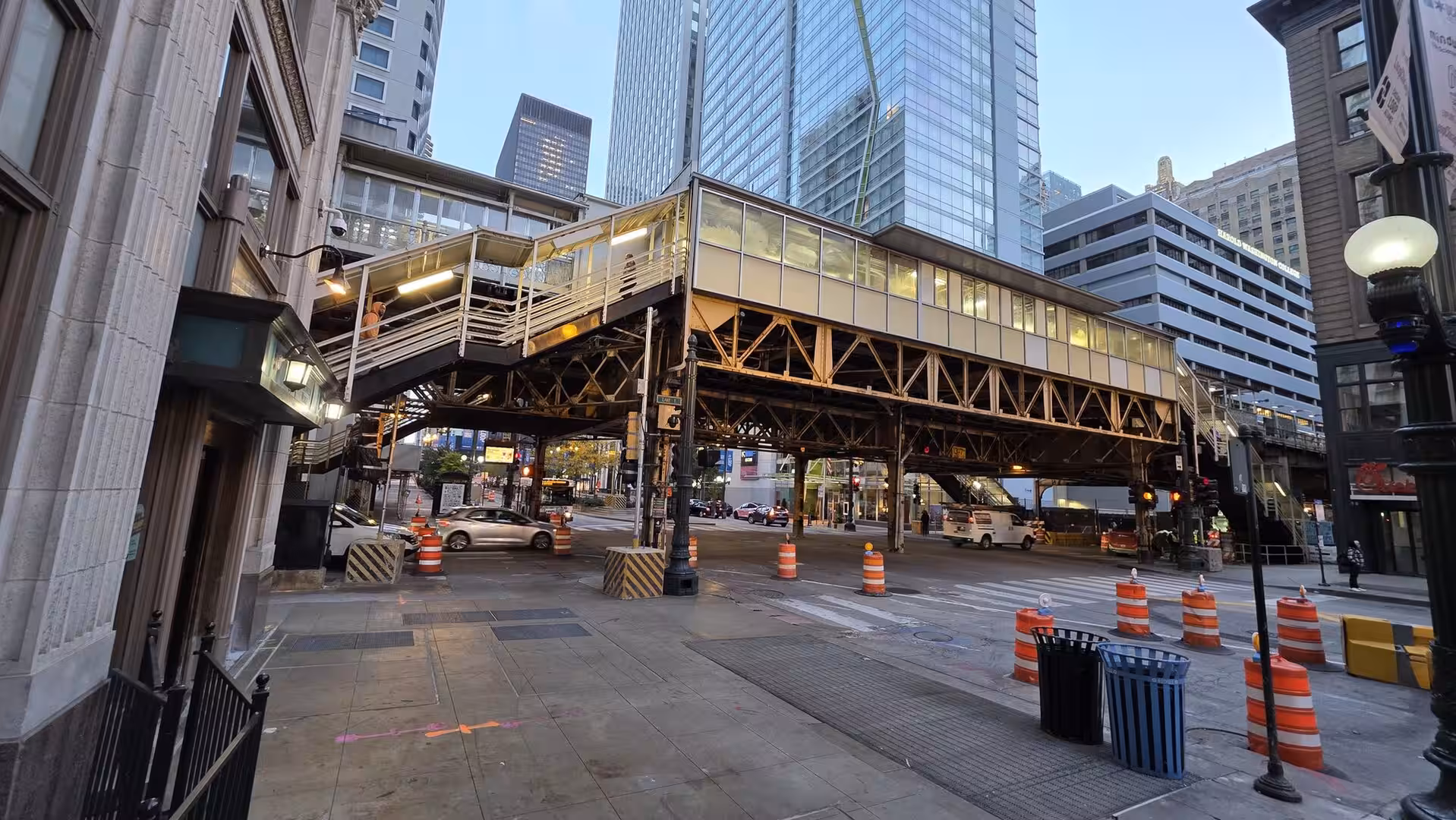 Elevated Chicago train station spanning a downtown intersection surrounded by modern skyscrapers at dusk