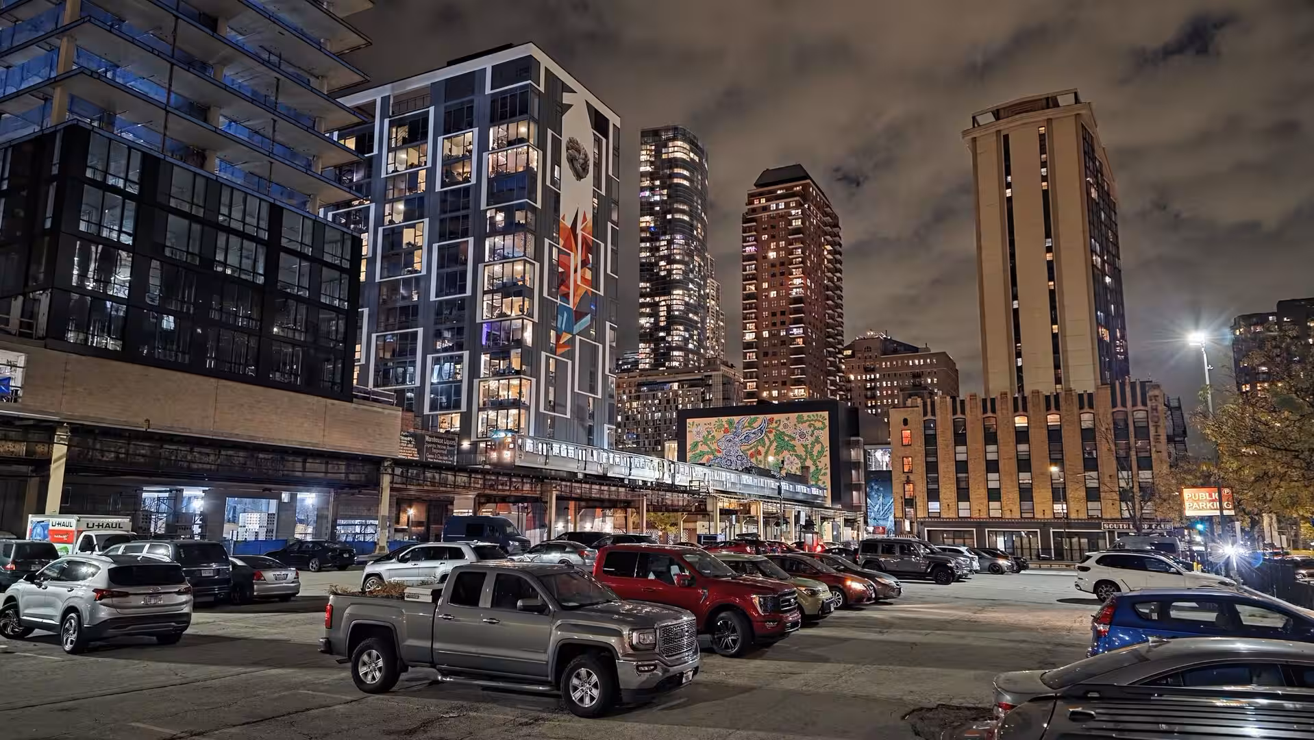 Chicago elevated train passing through downtown skyscrapers above a parking lot at night
