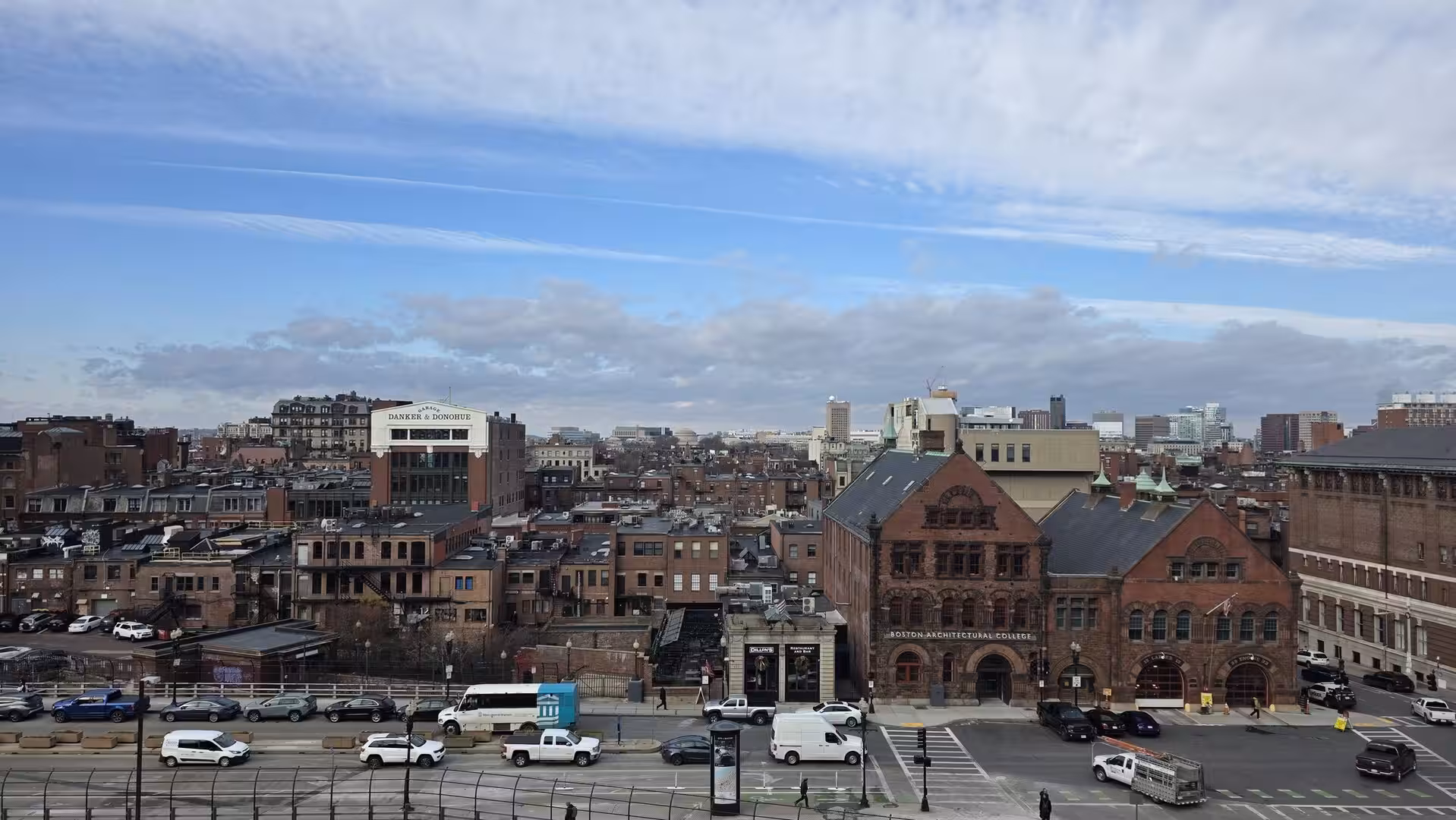 Panoramic view across Boston’s Back Bay with historic brick architecture, busy streets, and the Boston Architectural College under dramatic winter clouds.