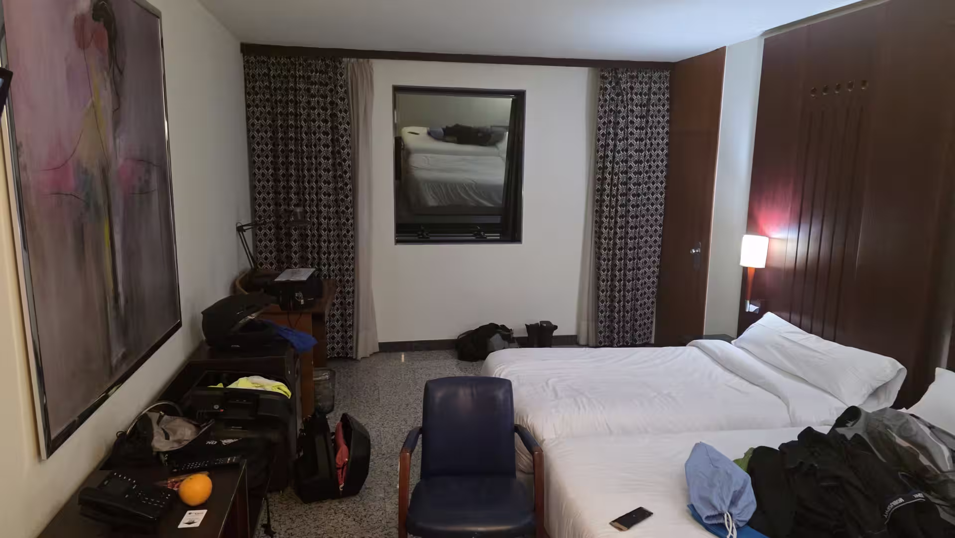 Hotel room with twin beds, a desk, and travel gear arranged after arrival.