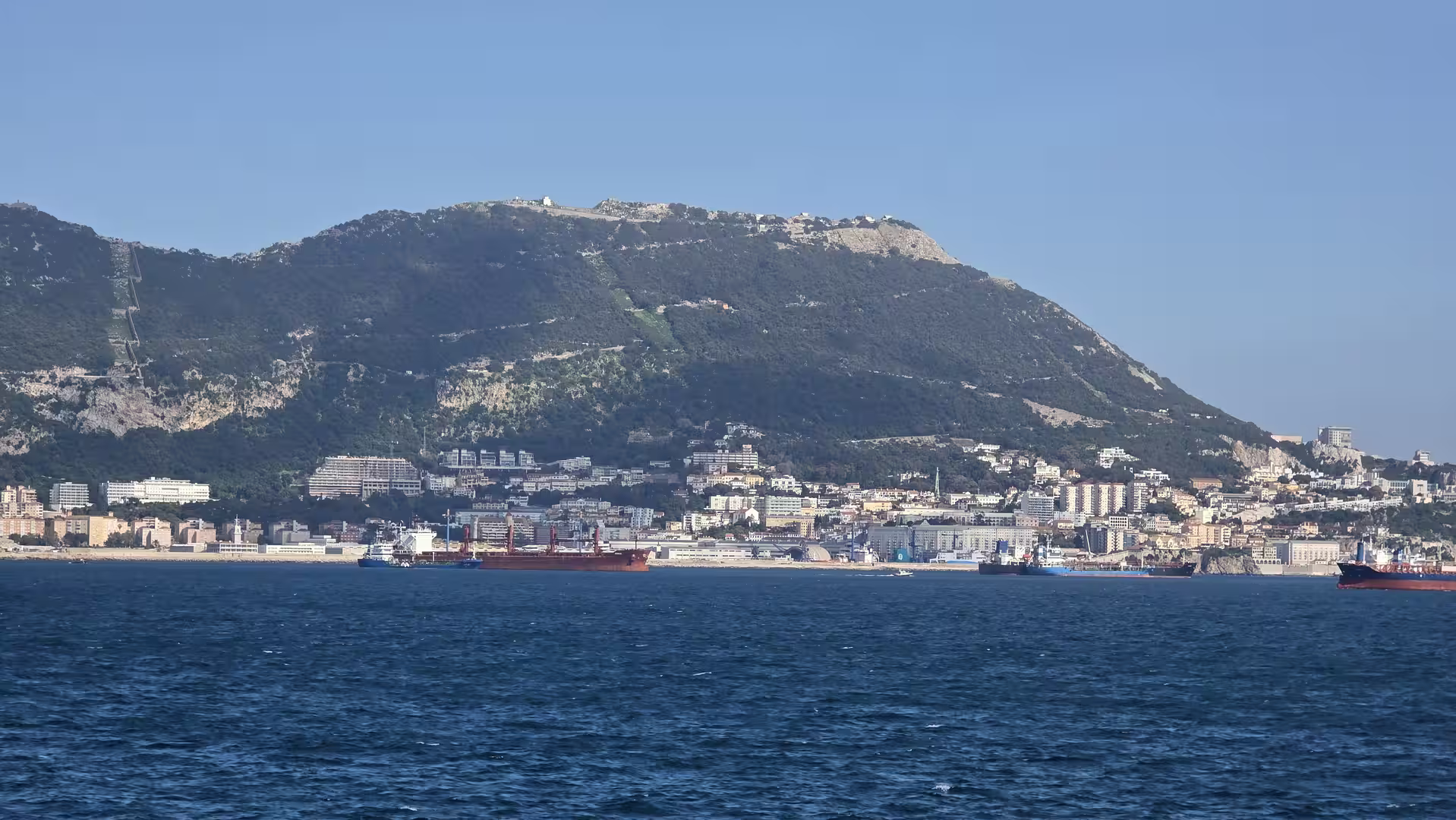 View of Gibraltar's coastline beneath the Rock with ships anchored in the Strait of Gibraltar.