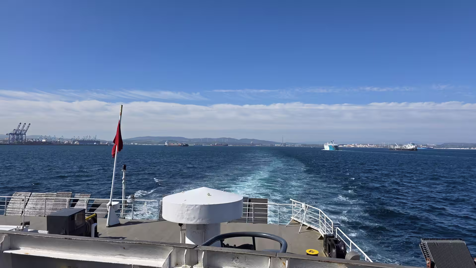View from a ferry crossing the Strait of Gibraltar with ships and port facilities in the distance.