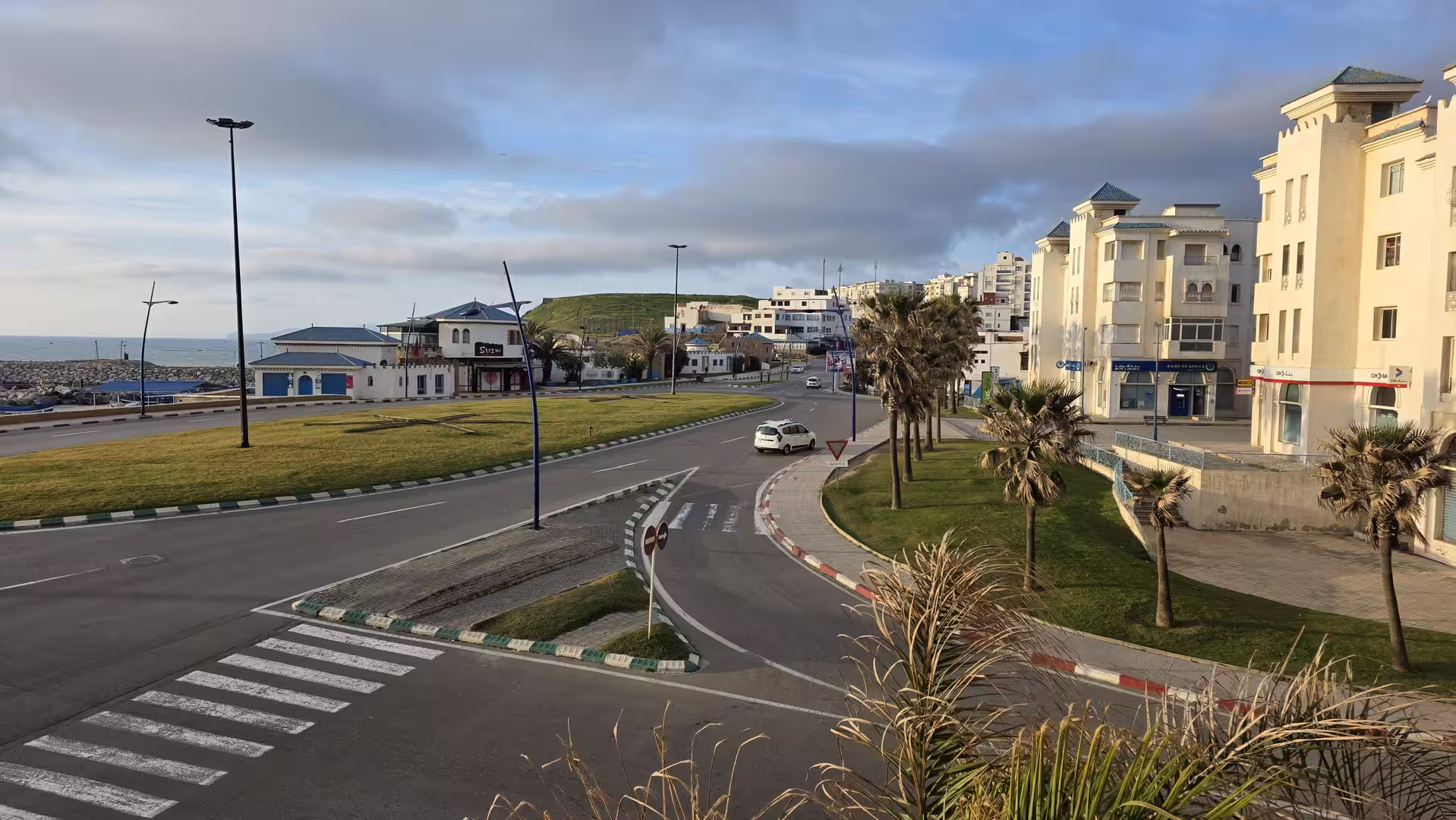 Early morning view of Fnideq on Morocco's Mediterranean coast with palm-lined streets and modern buildings.