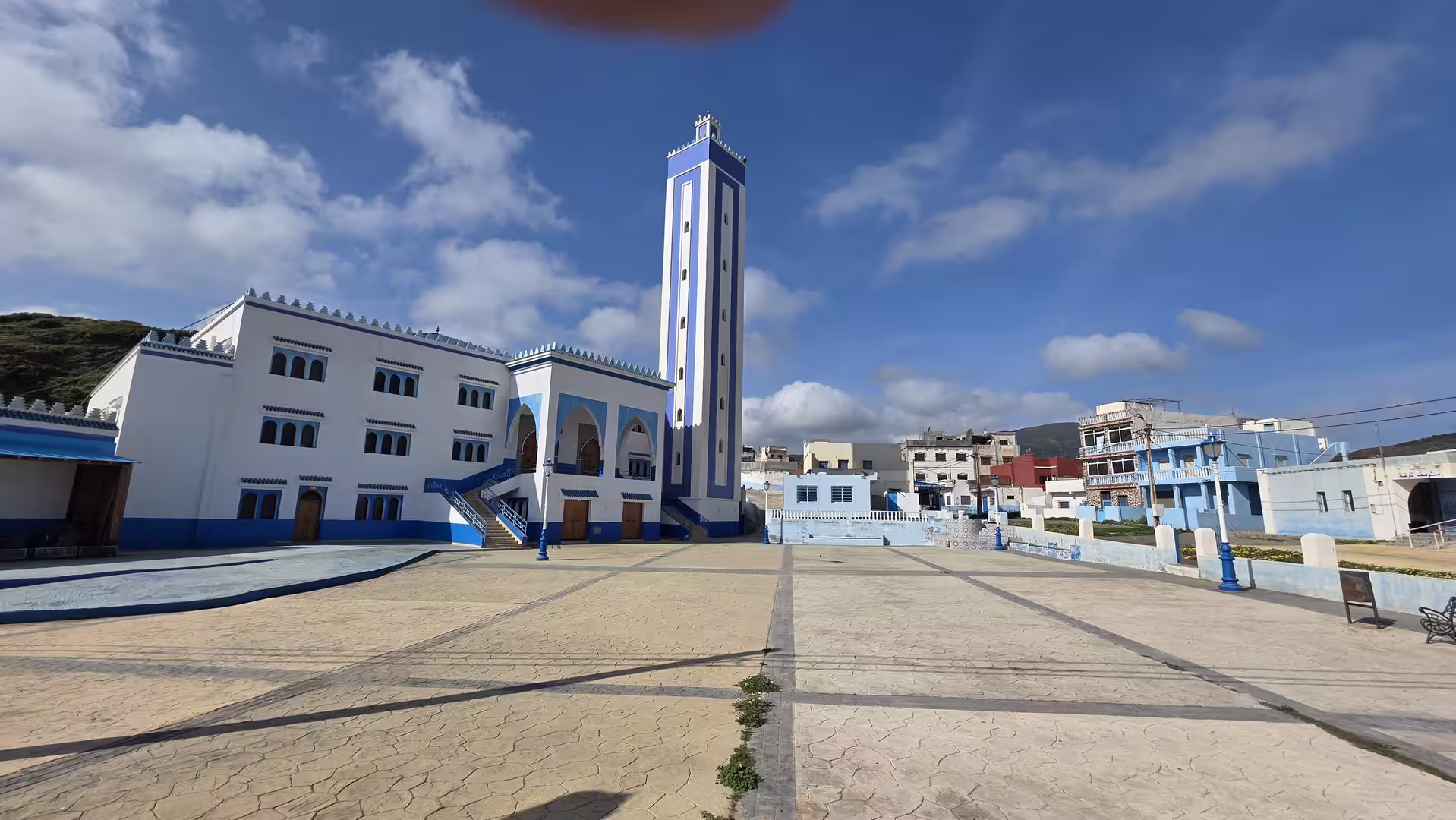 Modern blue-and-white mosque with a tall minaret near the Mediterranean coast of northern Morocco.