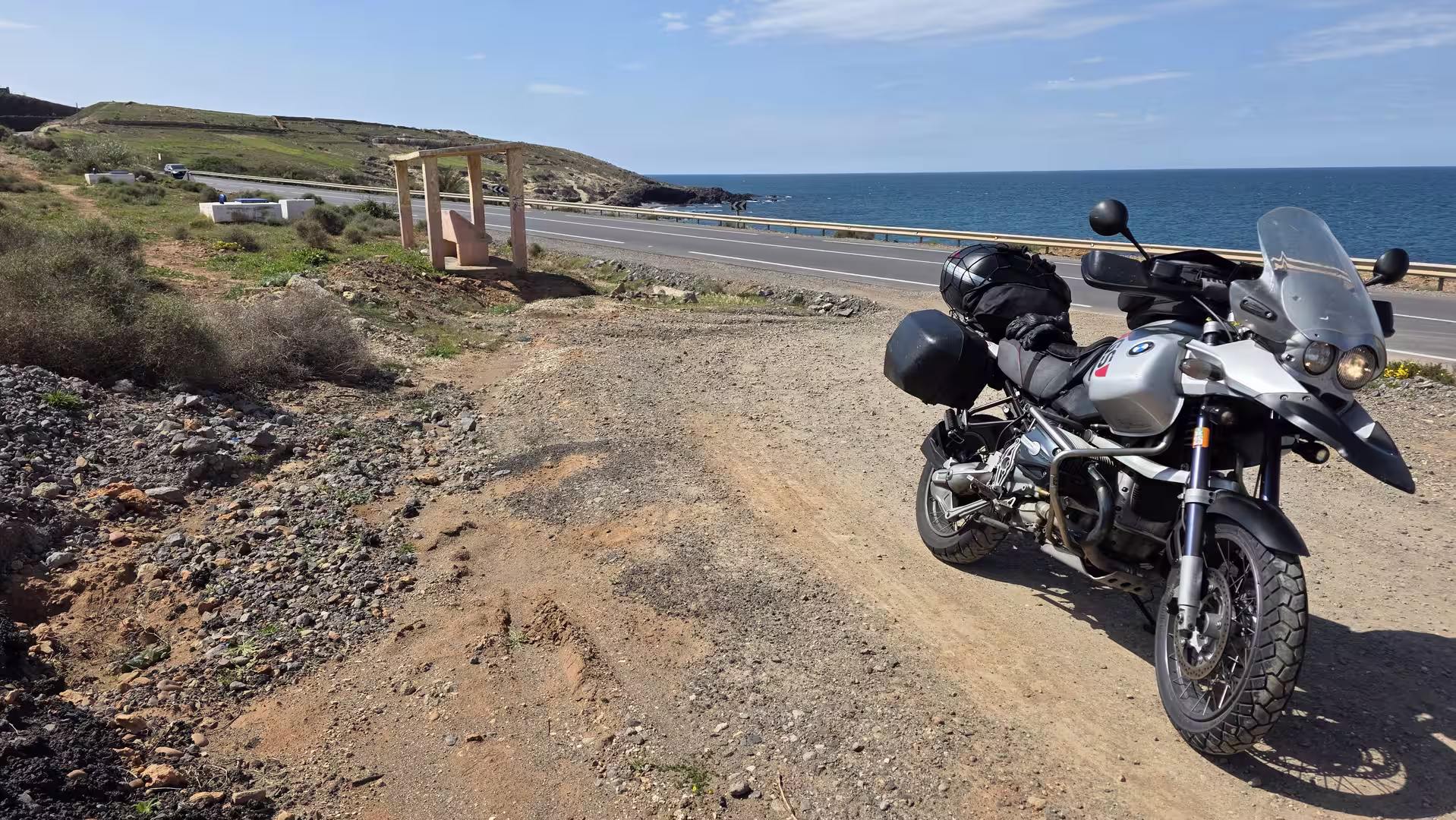 Adventure motorcycle parked beside a coastal road overlooking the Mediterranean Sea in northern Morocco.