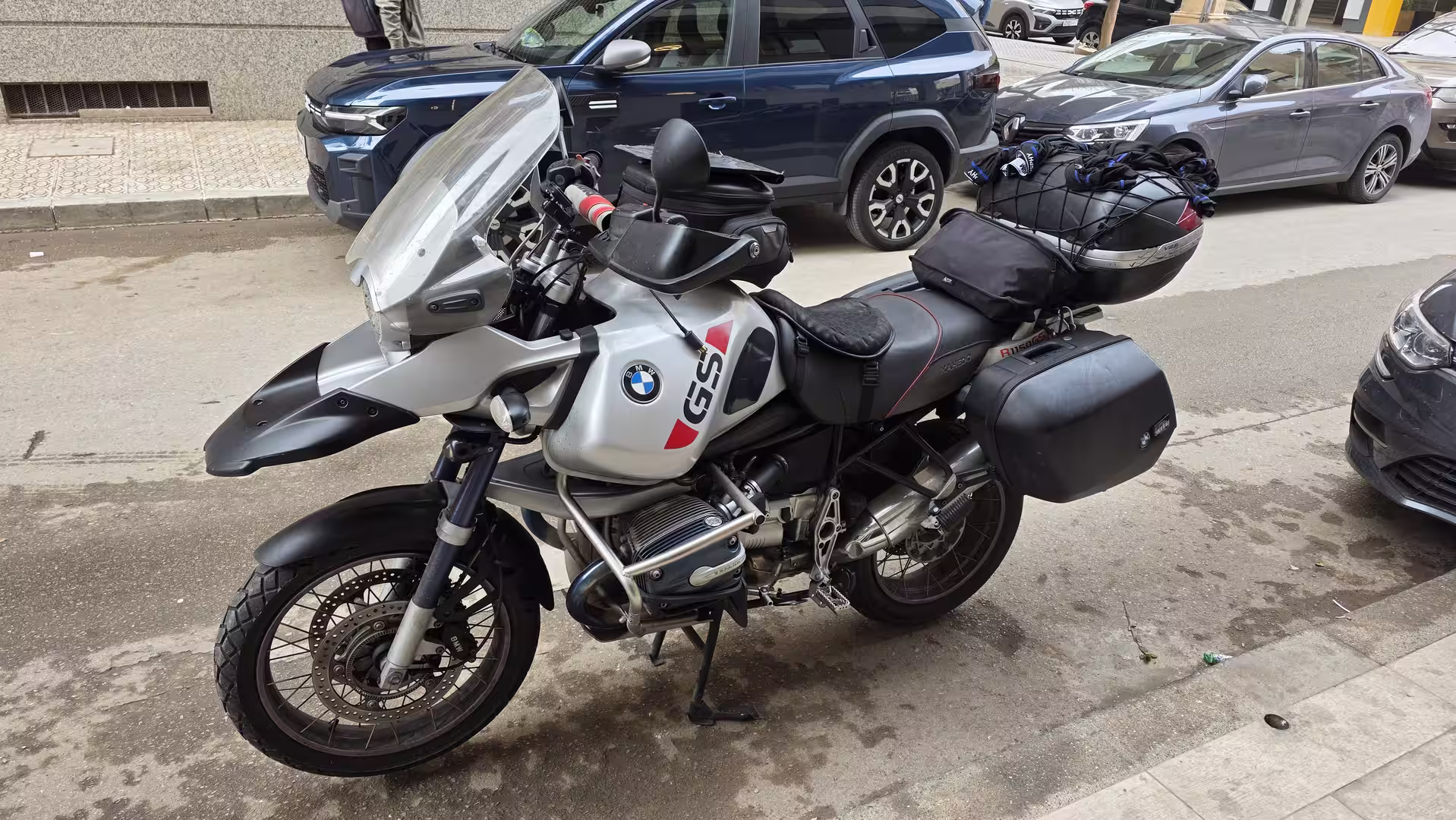 Fully loaded BMW GS adventure motorcycle parked on a city street before departure.