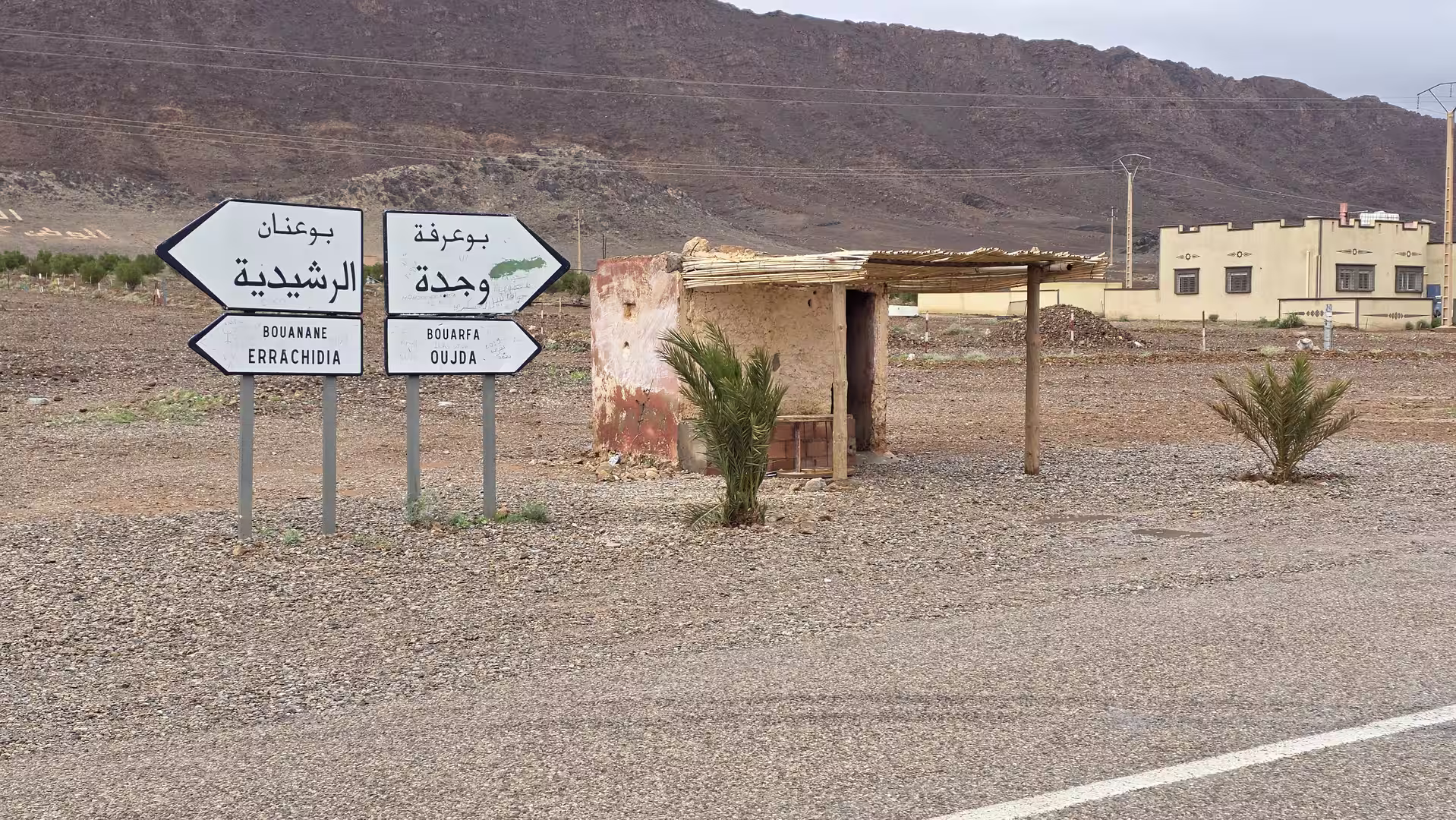 Road signs pointing toward Bouarfa, Oujda, Bouanane and Errachidia at a remote desert junction in Morocco.