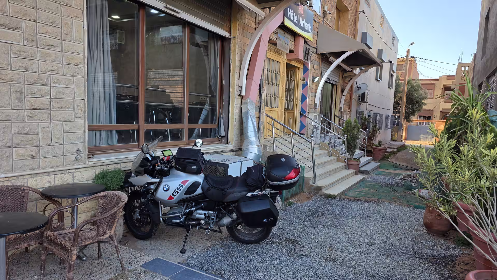 Loaded touring motorcycle parked outside a small hotel entrance in Bouarfa, eastern Morocco.
