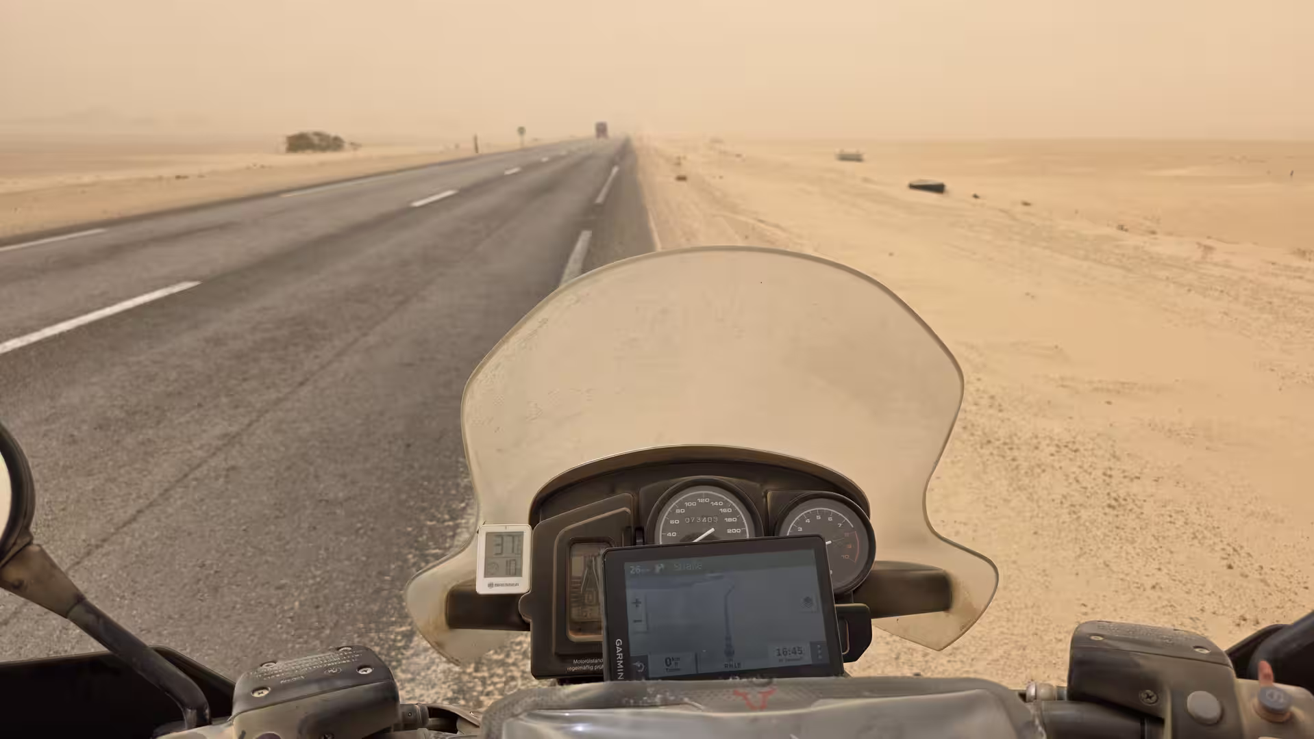 View from a touring motorcycle stopped on a desert highway during a sandstorm near Boujdour in Western Sahara.