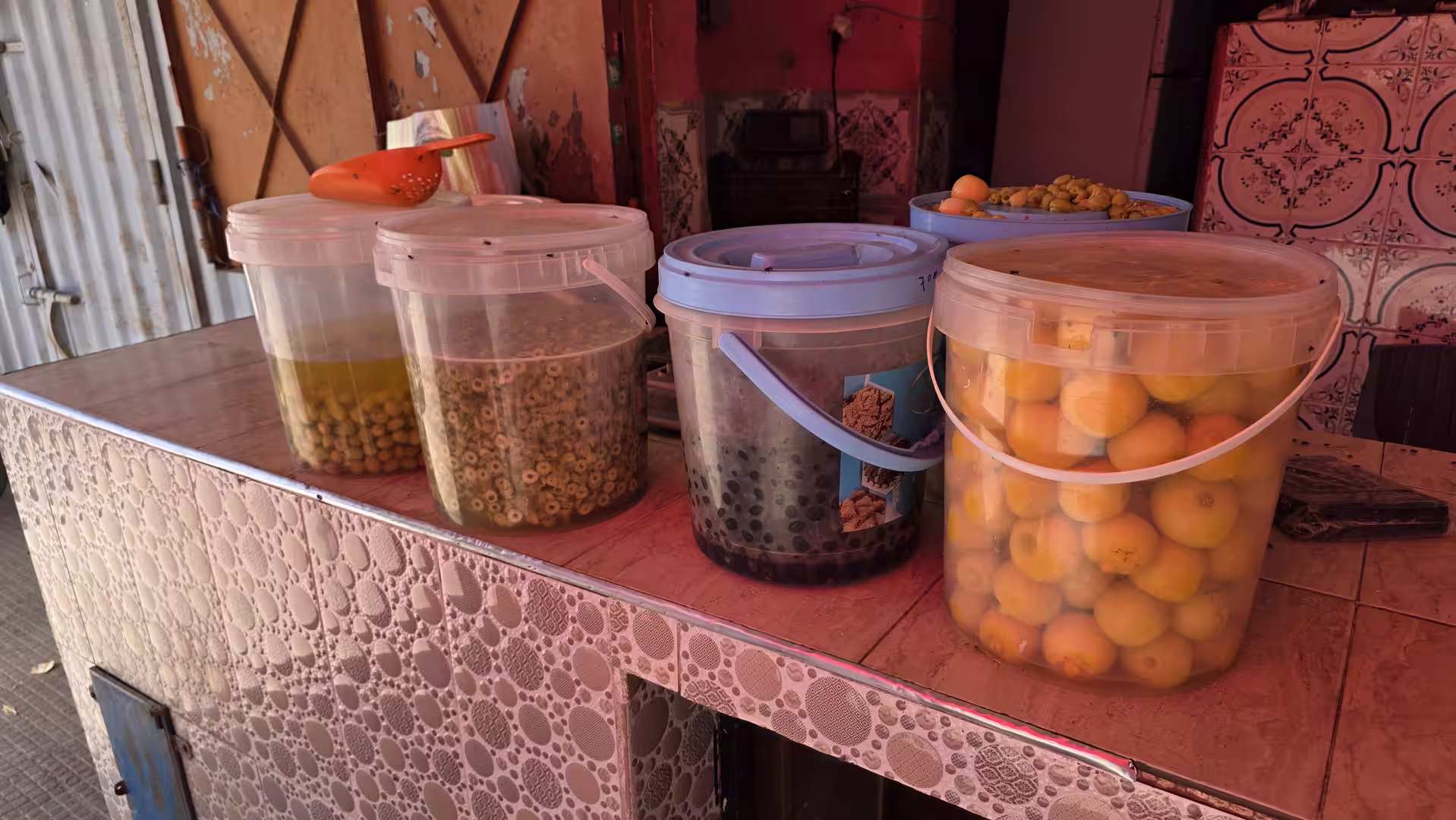 Large buckets of preserved olives and whole preserved lemons displayed at a traditional market stall.