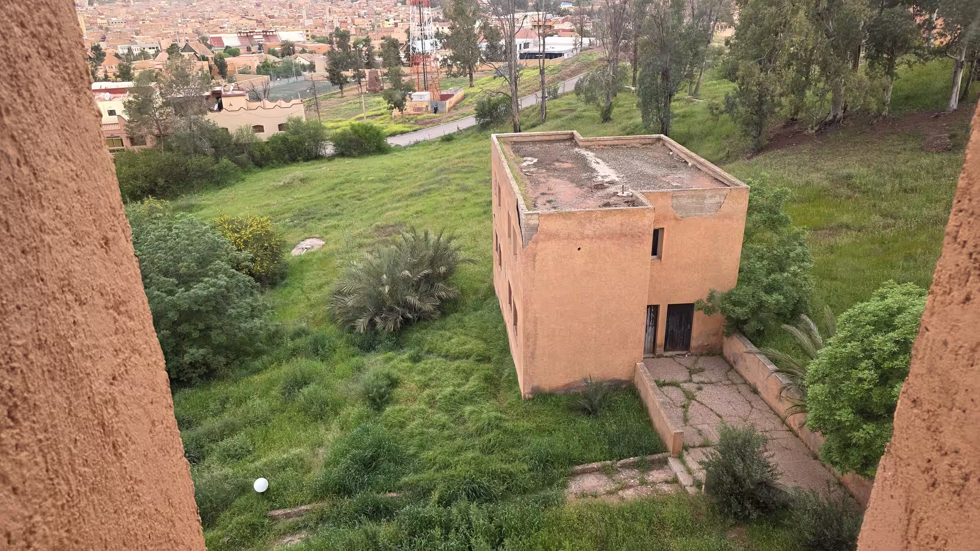 View from Hotel Continental in Khénifra overlooking a green hillside, hotel grounds, and the city in the background.