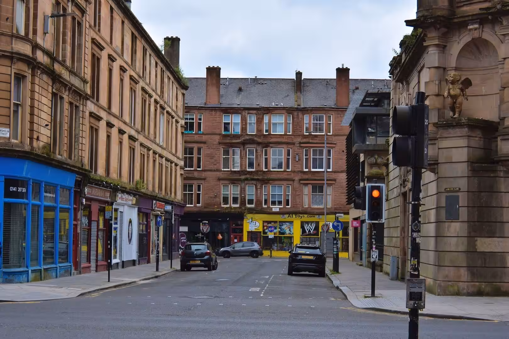 Red sandstone tenements ring a quiet corner with shops.